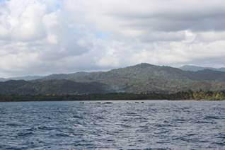 A large body of water with a mountain in the background

Description automatically generated