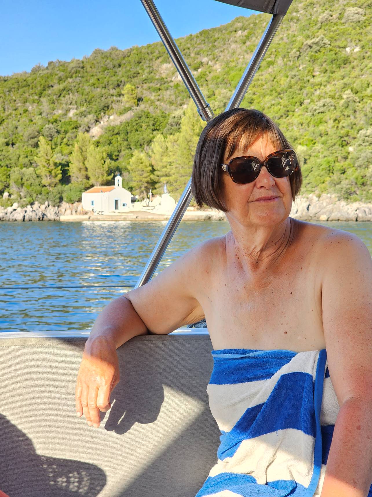 A person wearing sunglasses and a towel on a boat

Description automatically generated