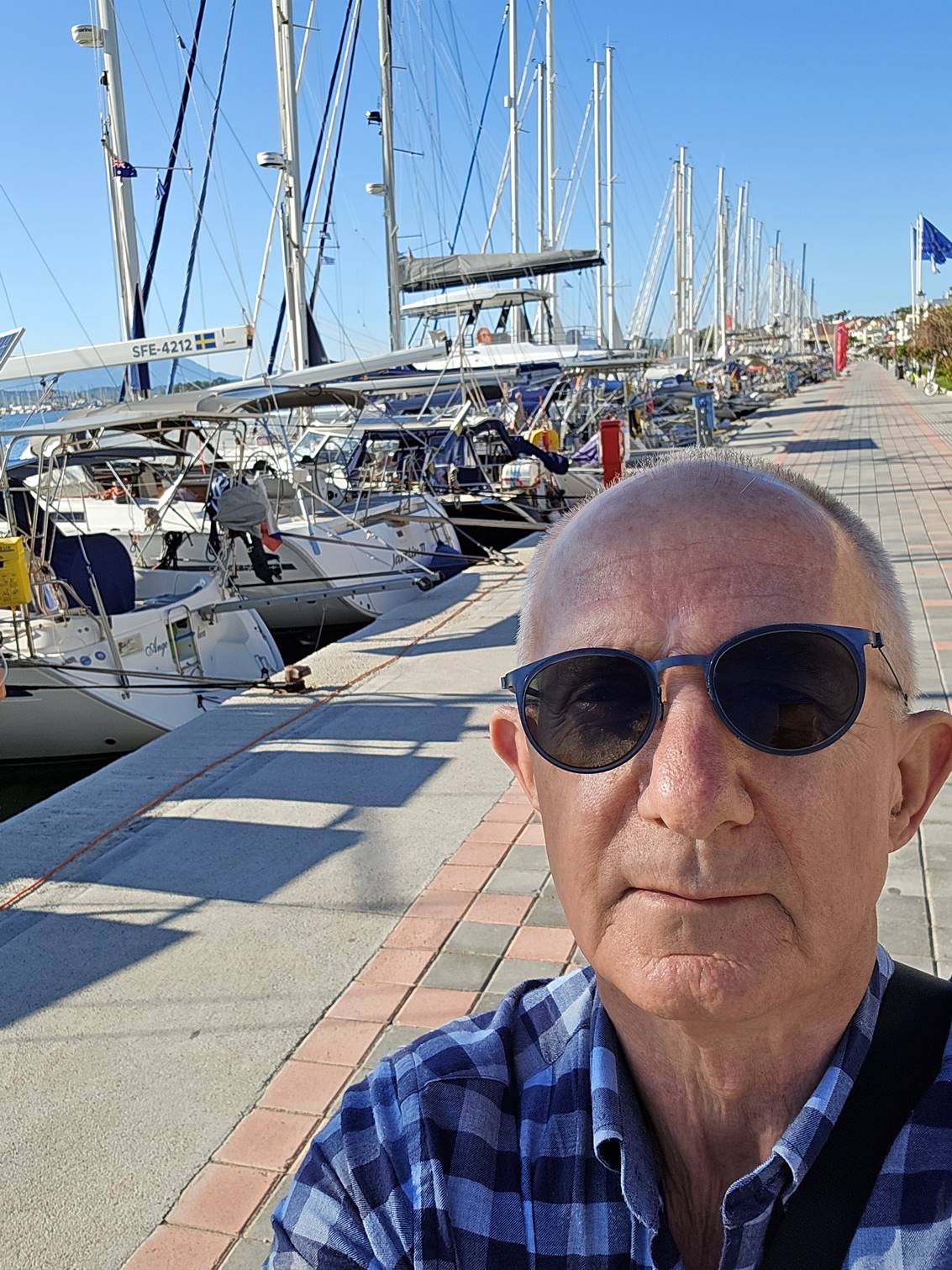 A person wearing sunglasses and sitting on a sidewalk

Description automatically generated