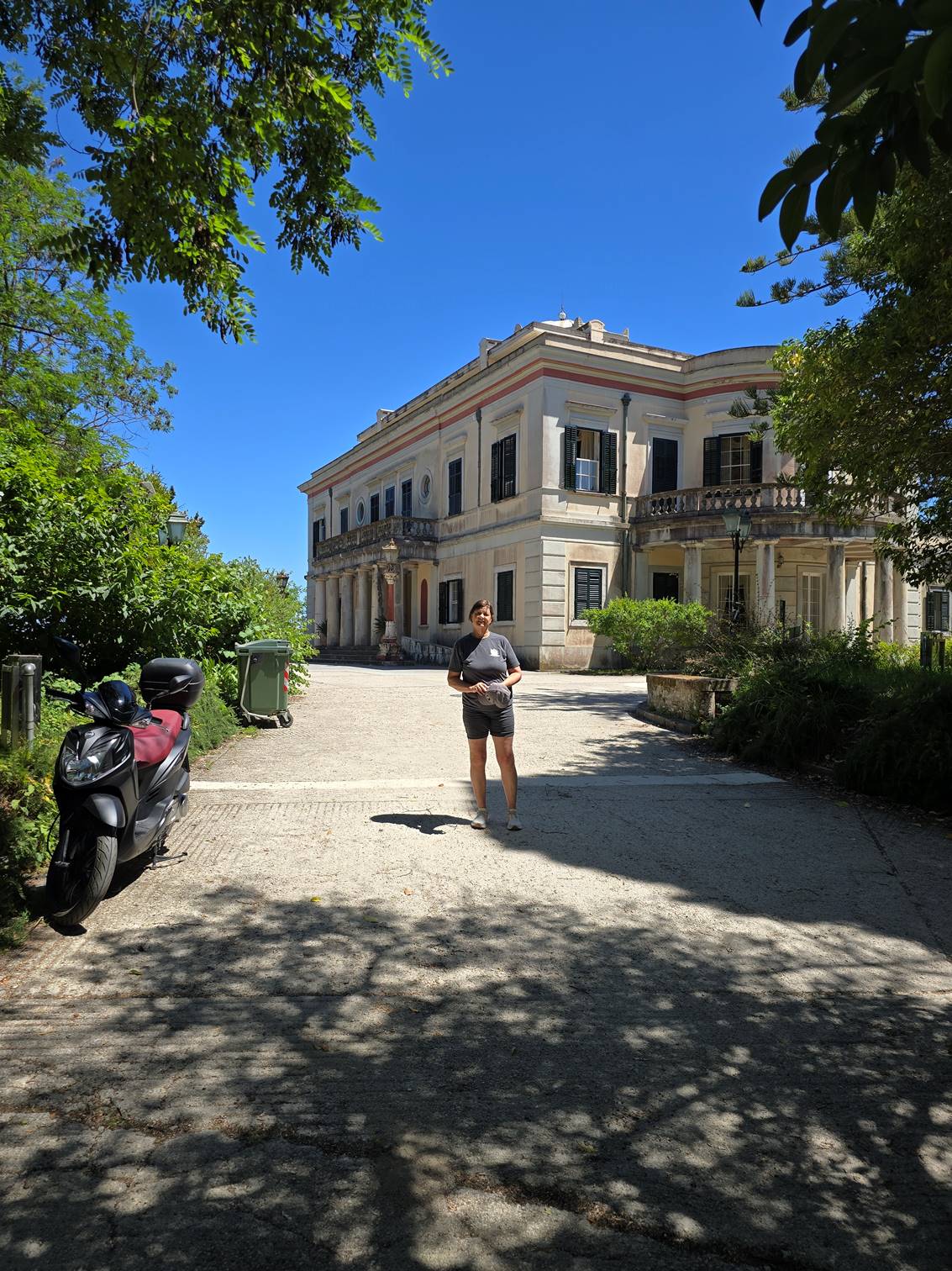 A person standing on a gravel path with a building in the background

Description automatically generated