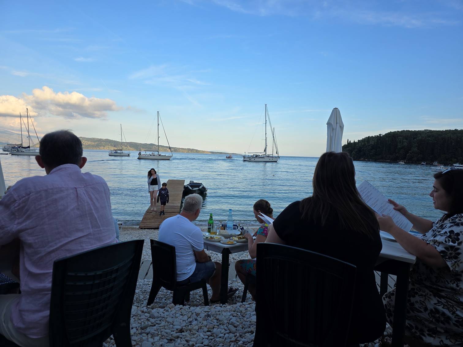 A group of people sitting at a table on a beach

Description automatically generated