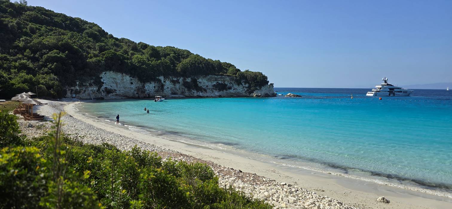 A beach with blue water and trees

Description automatically generated